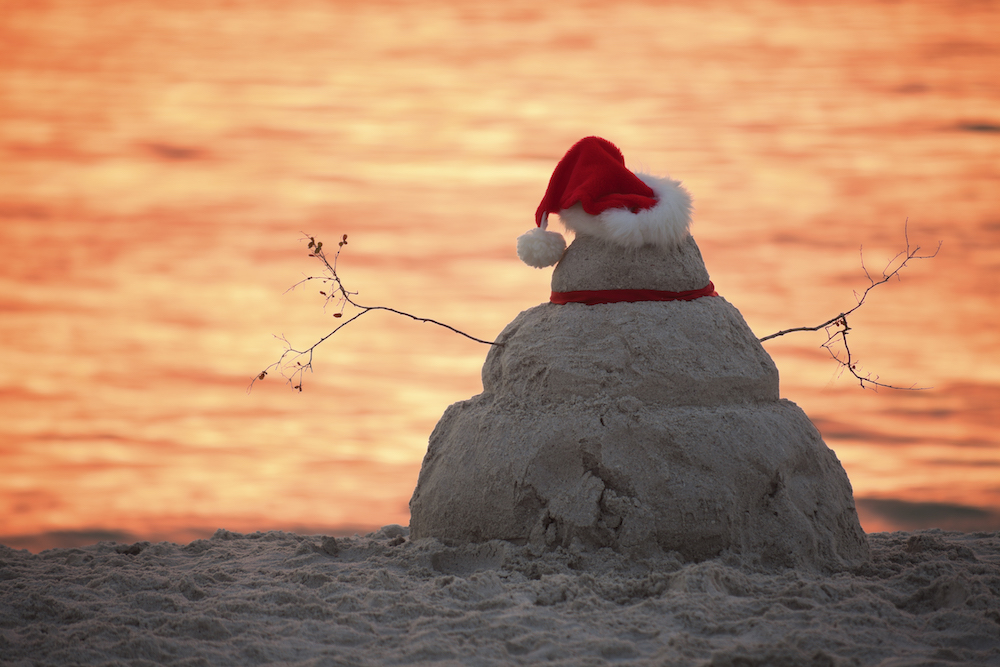 snowman made out of sand on the beach at sunset
